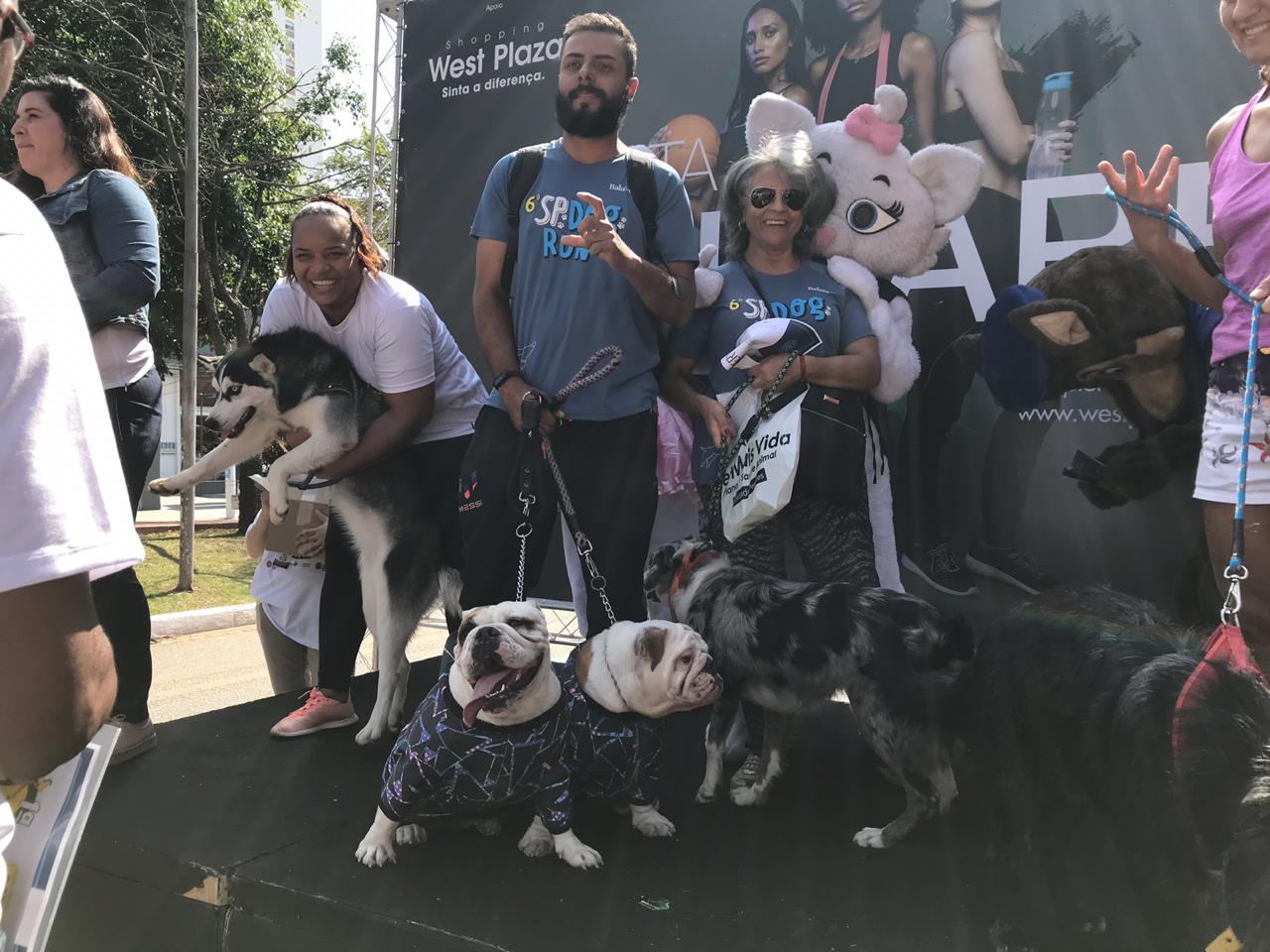 Momento de premiação do evento, com donos e pets no palco com plano de fundo contendo nome do evento Agita Sumaré e logos dos realizadores e parceiros